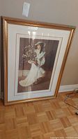 Full view of framed signed print showing the woman in white holding flowers with the entire frame visible
