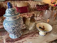 Photo showing ginger jar, ceramic rooster figurine, and rooster motif fruit bowl on marble surface