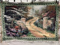 Full view of Thomas Kinkade woven tapestry throw/showing detailed garden path scene, brick pillars, trees, flowers, border, and fringe.