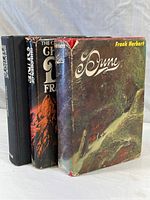 Three hardcover Dune novels standing side by side showing spines and front covers with some dust jacket wear.