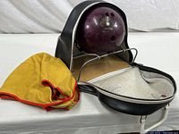 Bowling ball in open carrying case with fabric ball cleaner beside it on table