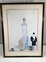 Photo showing entire framed Vogue cover poster with the tall woman and man illustration, under glass with double matting and gold and black frame.