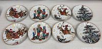 Photo of all eight plates arranged in two rows, displaying four Santa-claus sleigh, nutcracker soldiers, reindeer, and Christmas tree designs, on a neutral surface.