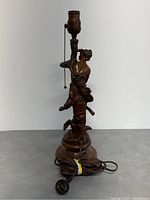 Front view of the antique French figurative table lamp showing female figure and light socket with pull chain. Lamp base and electric cord visible.