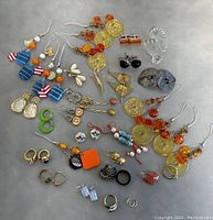Wide view showing most of the jewelry including rings, earrings, cufflinks, and tags spread on a surface.