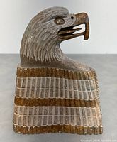 Front view of the eagle head stone carving showing detailed feathers and beak.