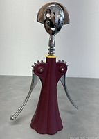 Front view of Alessi Anna G corkscrew showing smiling face head and extended metal lever arms.