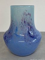 Front view showing the bulbous body and the organic purple spot pattern on light blue glass.