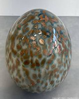 Close-up of the top and sides of the Murano glass egg showing detailed speckled gold and blue pattern.