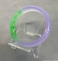 Jadeite bangle bracelet on clear display stand, front view