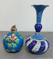 Photo of a round blue Limoges painted lamp with colorful floral patterns and a Persian enamelled metal vase with blue and white enamel designs.