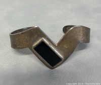 Silver cuff bracelet with a black onyx rectangular stone showing tarnish and wear.