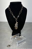 Full lot shown on black display and clear stand with necklace featuring heart locket, another necklace with multiple pendants, plus three pairs of earrings including hoops, mother-of-pearl studs, and pearl dangles.