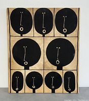 Front view of framed textile art showing grid of stylized black faces with minimal expression in simple shapes on beige background.