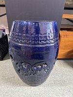 Front view showing textured bands and carved floral cutouts on blue ceramic garden stool.