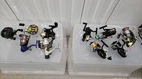 Overview of ten fishing reels arranged on two plastic bins