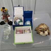 Full view of all items on display surface including the clown figurine, Easter eggs in boxes, Native Scratch Owl, painted globes, and crystal hippo figurine.