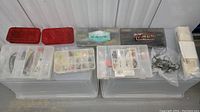 Photo of all fishing lure and hook containers including two red lids and several plastic boxes