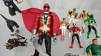 Photo showing large pirate-themed red-cape Power Ranger figure, multiple Power Rangers in various colors, and other small figures with accessories.