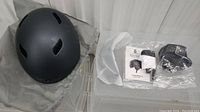 Dark grey helmet resting on fabric bag with loose accessories in plastic bags beside it.