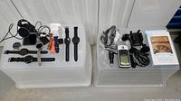 Top view of all items including smartwatches with bands and chargers, Garmin GPS 76 device and car holder, notebook mini fan boxed.