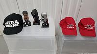 Three Star Wars bobblehead figures and caps displayed on clear risers, showing set contents