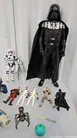 Collection of Star Wars action figures including Darth Vader, stormtroopers, and others, showing scale and condition.