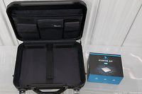 Open black laptop armor case with compartments and accessories pockets, next to boxed Raspberry Pi 4 Starter Kit