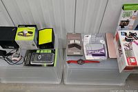 Photo showing two TV boxes, folding keyboards, a film scanner, two watches including Garmin and Swatch, and power adapter cables