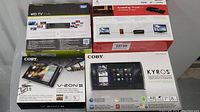 Photo showing four boxed electronic devices: WD TV Live, Iomega ScreenPlay TV Link DX, COBY V-Zon, and COBY Kyros tablet.