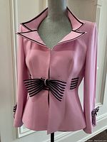 Front view of pink blazer on mannequin showing black organza bow at waist and cuffs