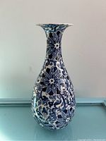 Full view of the tall slender vase with blue and white floral design.