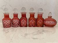 Front view of all six cranberry glass perfume bottles in a row.