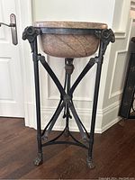 Frontal view of marble bowl supported by bronze stand with ram head details and claw feet