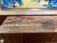 Full spread of flatware laid out in rows on marble top