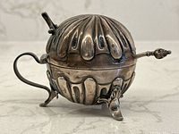 Front-side view of closed spherical pot with spoon inserted