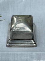Closed sterling silver ring box showing stepped base and domed lid with surface scratches.