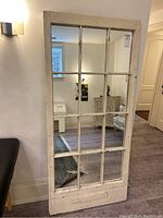 Full front view of distressed white window frame mirror showing twelve mirrored panes and chippy paint finish.