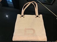 Front view of tote showing canvas body, leather trim and D emblem
