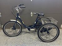 Left side view showing entire tricycle, front wheel, frame, rear wheels and basket