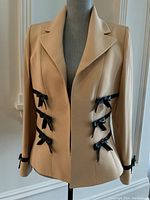 Front view of blazer showing three black ribbon bows on front closure