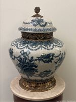 Front view of full urn showing crackle glazed porcelain body, blue floral pattern, brass band and base