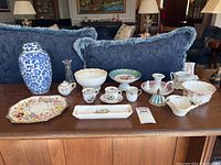 Full display of vintage china collection with various plates, cups, bowls, and ginger jar on a wooden table