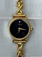 Front view of watch face showing black dial, crystal marker, hands and fluted bezel