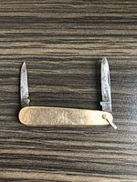 Knife open showing two blades extended and gold handle with monogram