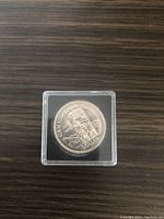 Top side of Canadian silver dollar coin showing a totem pole design with inscriptions.