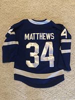 Back of the blue hockey jersey showing 'MATTHEWS' and number '34' in white.