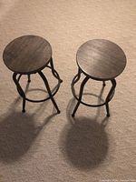 Top view of two bar stools showing round wooden seats and metal legs.