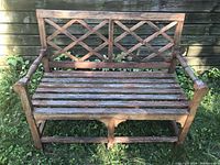 Front view of the wooden outdoor bench showing lattice back and slatted seat with armrests.