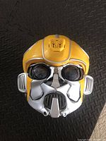Front view of Bumblebee-themed helmet showing it is yellow with silver and black facial details and a distinctive Bumblebee logo on top.